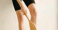 Femme effectuant un brossage à sec des jambes avec une brosse en bois pour réduire la cellulite naturellement
