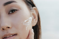 Femme appliquant un soin sur son visage pour unifier le teint et atténuer les taches brunes